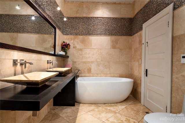 bathroom with tile flooring, tile walls, a bath to relax in, toilet, and vanity