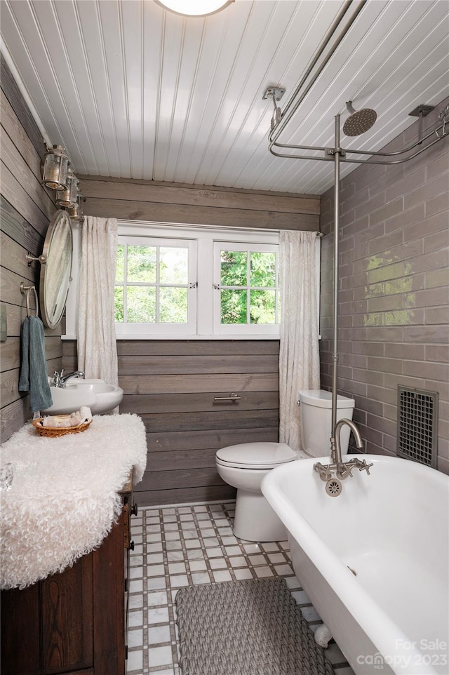 bathroom featuring plenty of natural light, toilet, and wood walls