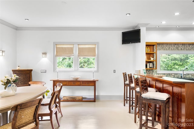 dining area featuring a healthy amount of sunlight, ornamental molding, light hardwood / wood-style floors, and sink