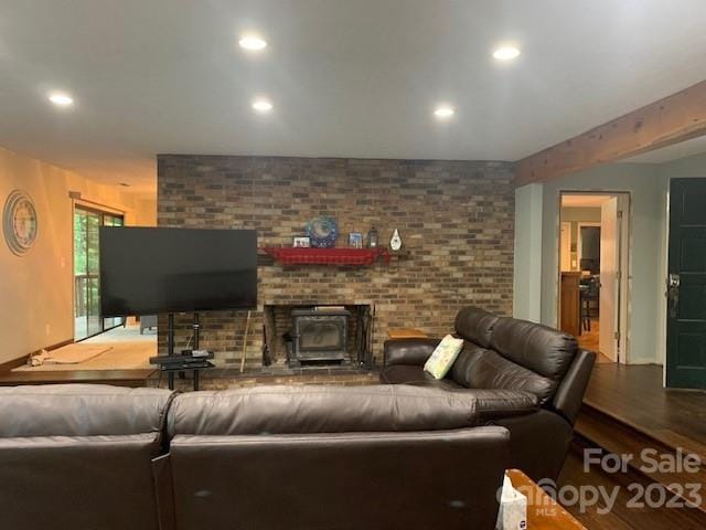 living room with a brick fireplace, brick wall, hardwood / wood-style floors, and a wood stove