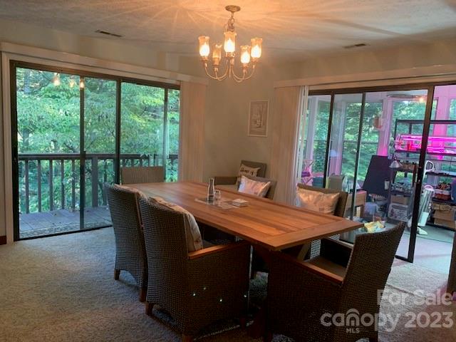 dining area featuring light colored carpet, a healthy amount of sunlight, and an inviting chandelier