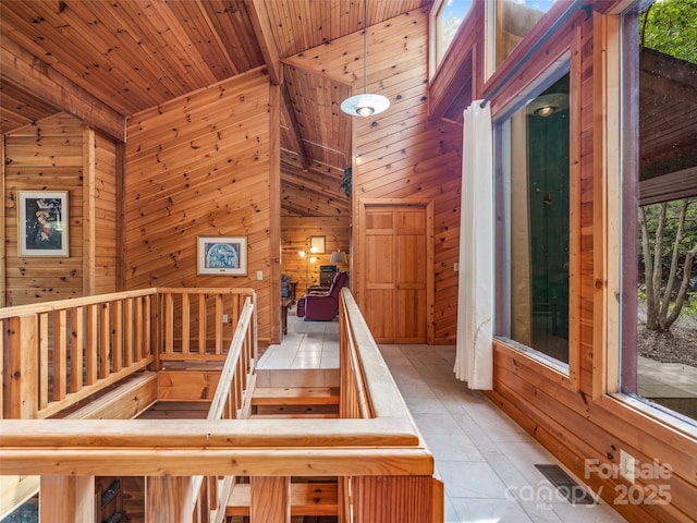 stairway with a wealth of natural light, high vaulted ceiling, wood ceiling, and wood walls