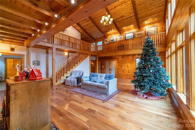 living room with an inviting chandelier, beam ceiling, wood walls, wood ceiling, and high vaulted ceiling