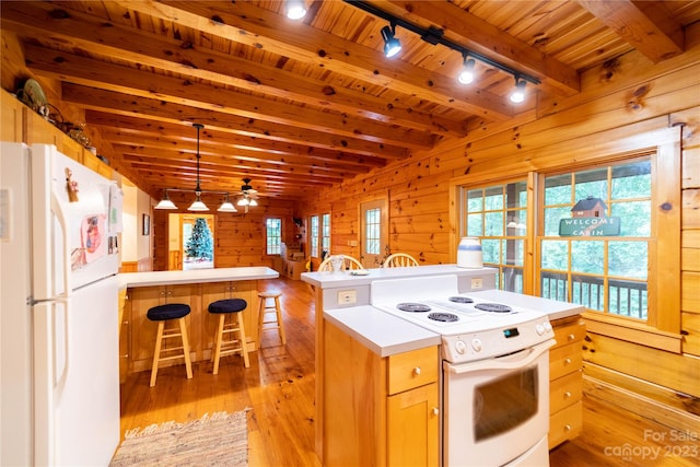 kitchen with white appliances, pendant lighting, ceiling fan, wood walls, and a center island