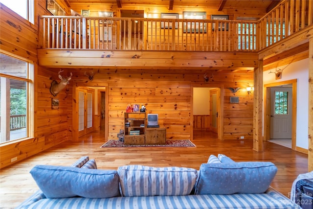 living room featuring a high ceiling, wood walls, wooden ceiling, and light hardwood / wood-style flooring