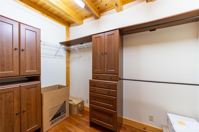 walk in closet with beamed ceiling and light hardwood / wood-style floors