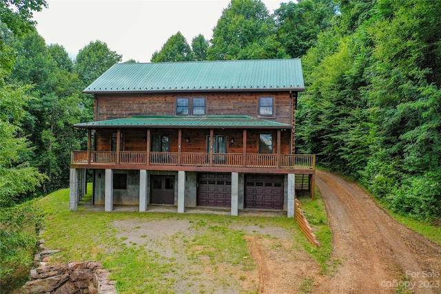 rear view of house featuring a lawn, a balcony, and a garage