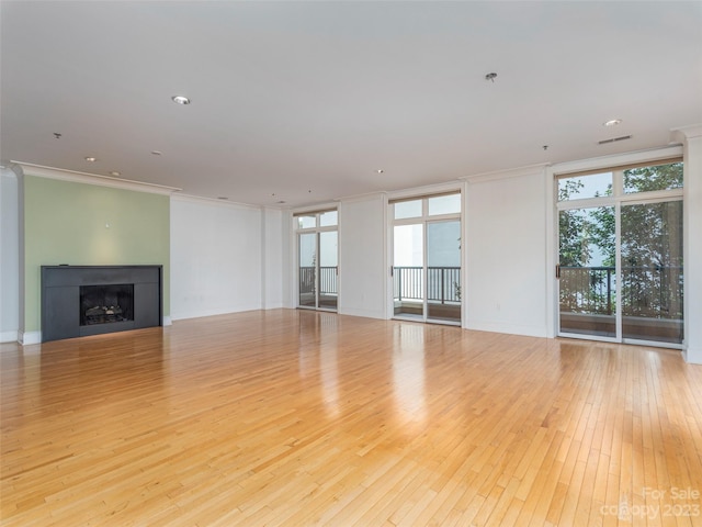 unfurnished living room featuring plenty of natural light, a wall of windows, light hardwood / wood-style floors, and crown molding