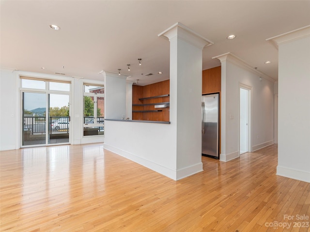 unfurnished living room with ornamental molding, light wood-type flooring, and decorative columns