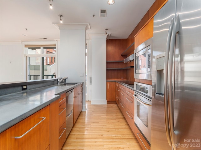 kitchen featuring wall chimney exhaust hood, stainless steel appliances, sink, and light hardwood / wood-style flooring