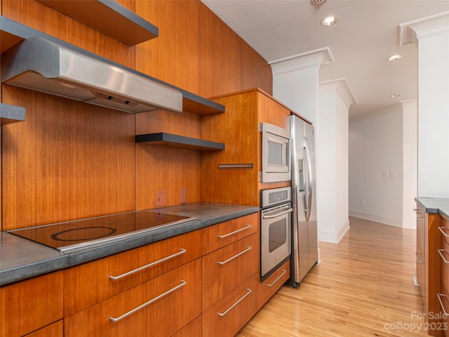 kitchen featuring wall chimney range hood, crown molding, light hardwood / wood-style flooring, and stainless steel appliances