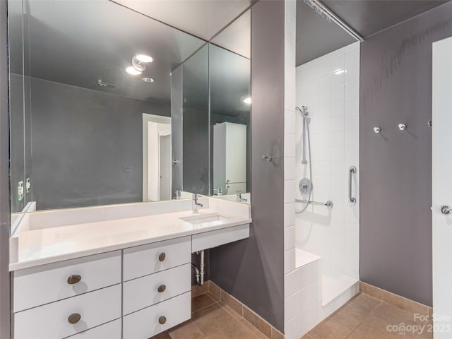 bathroom with tile floors, a tile shower, and vanity