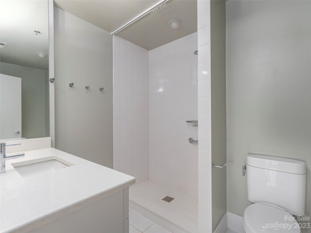 bathroom with tile floors, toilet, a tile shower, and vanity