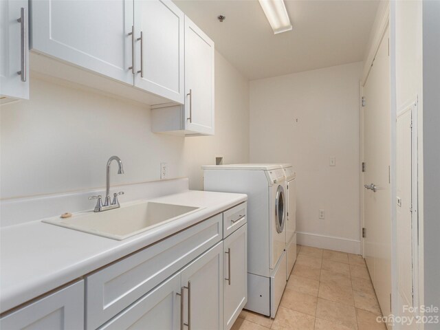 washroom with cabinets, light tile floors, sink, and washer and clothes dryer