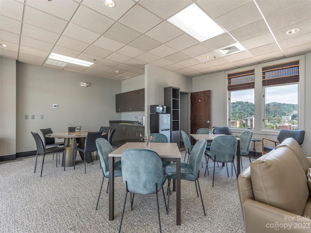 dining space with a drop ceiling and light carpet