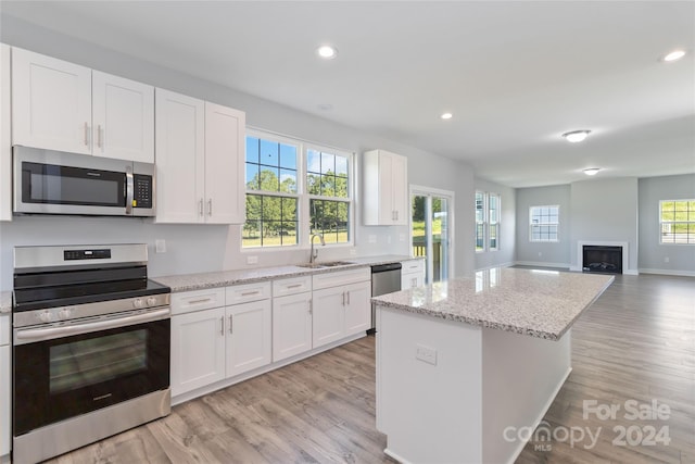 kitchen featuring white cabinets, light wood-type flooring, and stove