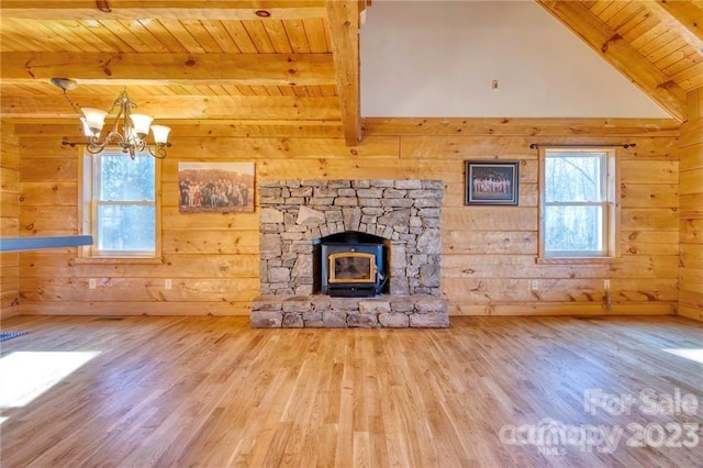 unfurnished living room with a notable chandelier, wood ceiling, light wood-type flooring, and a wood stove