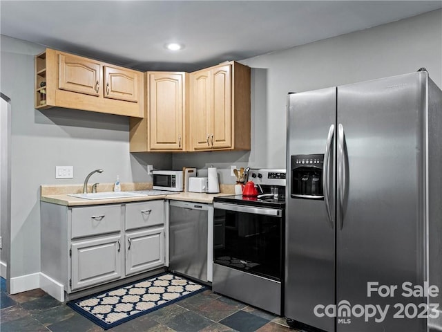 kitchen featuring light brown cabinets, sink, stainless steel appliances, and dark tile flooring