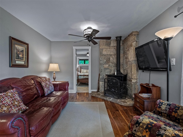 living room with ceiling fan, dark wood-type flooring, and a wood stove