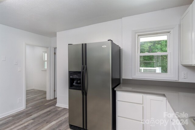 kitchen featuring stainless steel fridge with ice dispenser, light hardwood / wood-style flooring, and white cabinets