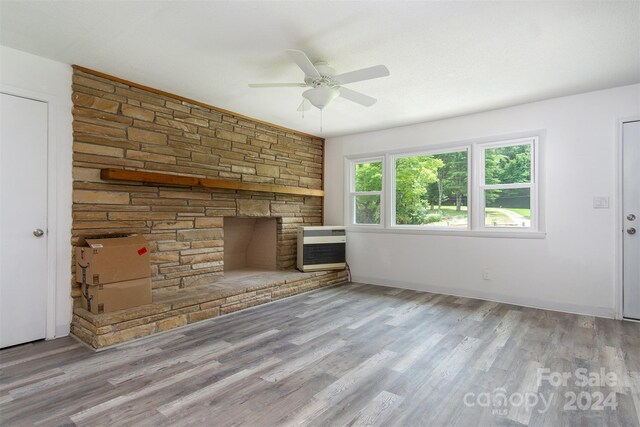 unfurnished living room featuring heating unit, a fireplace, ceiling fan, and light hardwood / wood-style flooring