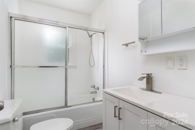 full bathroom featuring vanity, shower / bath combination with glass door, and toilet