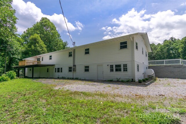 rear view of house featuring a wooden deck and a lawn