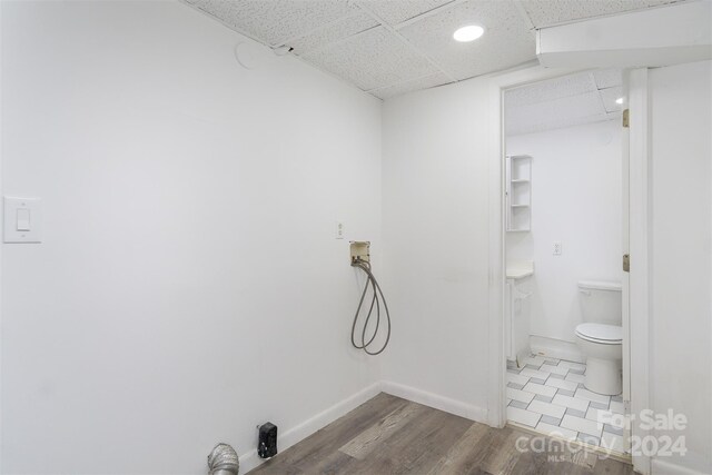 bathroom with a paneled ceiling, toilet, and hardwood / wood-style floors