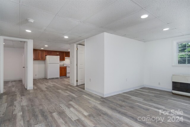 unfurnished living room featuring heating unit, a paneled ceiling, and light hardwood / wood-style floors