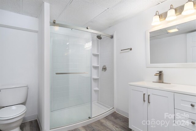 bathroom featuring wood-type flooring, vanity, an enclosed shower, and toilet