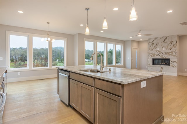 kitchen with pendant lighting, sink, stainless steel dishwasher, and an island with sink