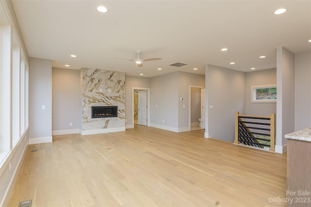 unfurnished living room featuring ceiling fan, a fireplace, and light wood-type flooring