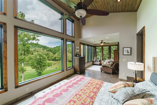 bedroom featuring wood ceiling, dark hardwood / wood-style flooring, ceiling fan, and a towering ceiling