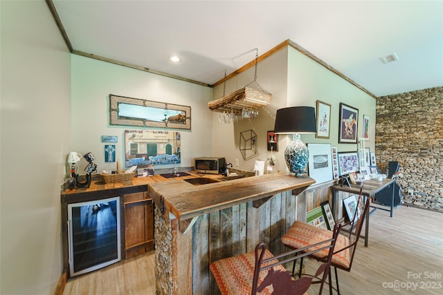 kitchen featuring crown molding, beverage cooler, and light wood-type flooring