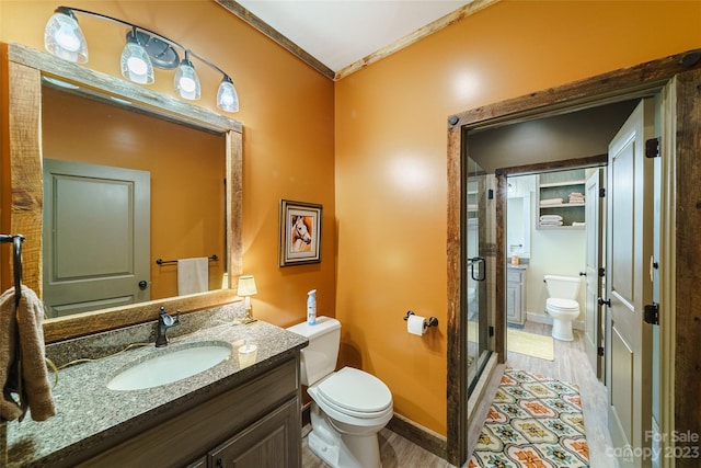 bathroom featuring toilet, vanity, wood-type flooring, ornamental molding, and walk in shower