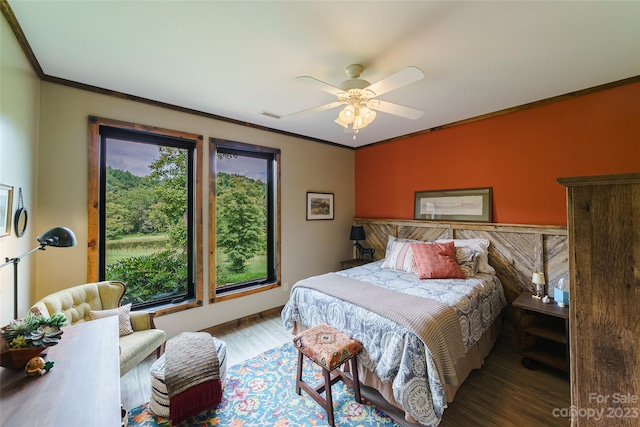 bedroom with ceiling fan, multiple windows, dark wood-type flooring, and ornamental molding