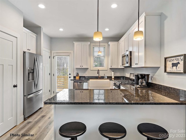 kitchen with a kitchen breakfast bar, decorative light fixtures, dark stone countertops, and stainless steel appliances