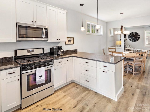 kitchen featuring an inviting chandelier, stainless steel appliances, decorative light fixtures, and light wood-type flooring