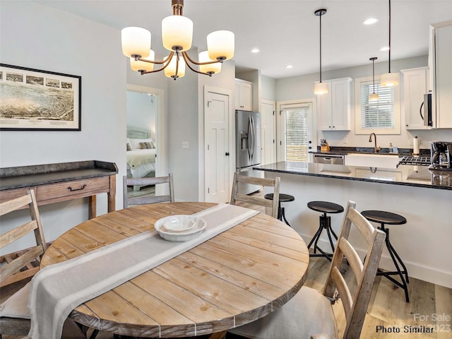 dining room with an inviting chandelier, sink, and light hardwood / wood-style floors