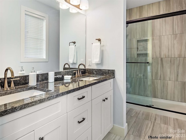 bathroom with dual sinks, oversized vanity, tile flooring, and a shower with door