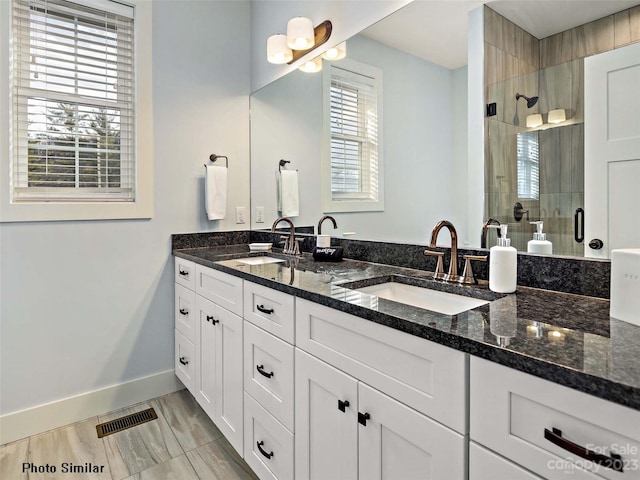 bathroom with tile flooring, a shower with shower door, large vanity, and dual sinks