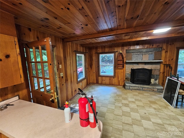 living room featuring wooden walls and a stone fireplace