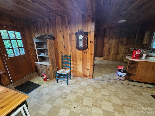 interior space with sink, wooden walls, wooden ceiling, and light tile flooring