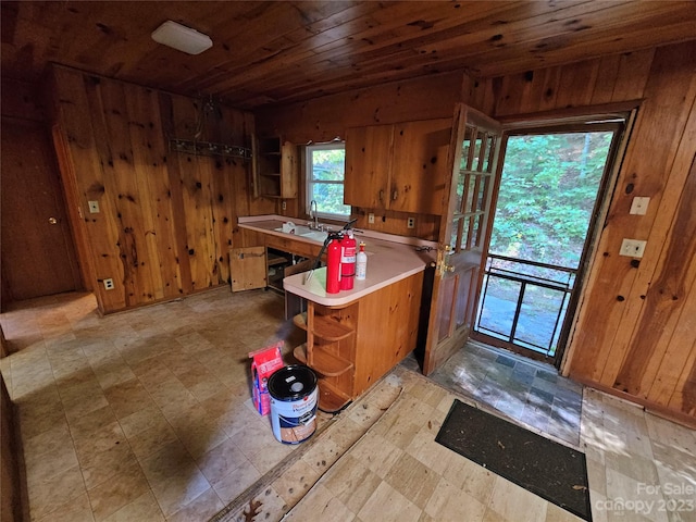 kitchen with kitchen peninsula, wood walls, light tile floors, and wooden ceiling