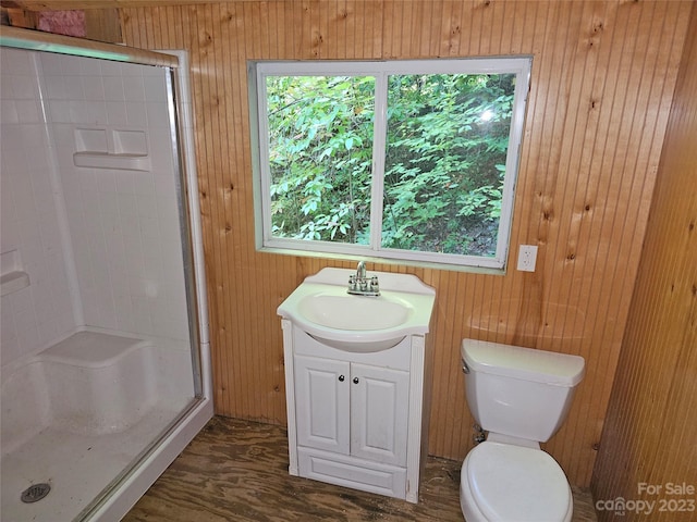 bathroom featuring walk in shower, wood-type flooring, wooden walls, toilet, and vanity