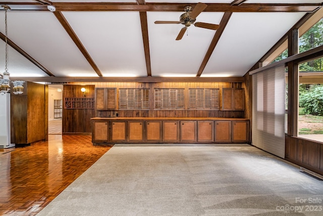 interior space featuring lofted ceiling with beams, wooden walls, ceiling fan with notable chandelier, and dark parquet flooring