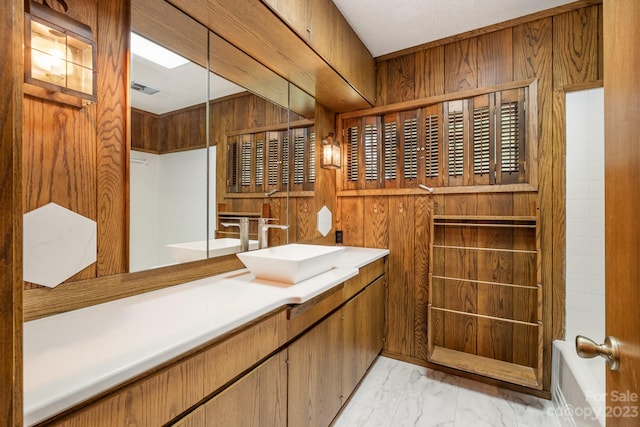 bathroom featuring wooden walls, a textured ceiling, tile flooring, and large vanity