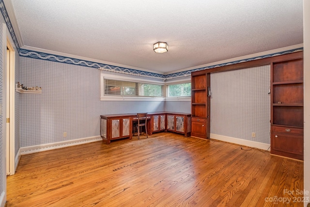 spare room with a textured ceiling, light hardwood / wood-style floors, and crown molding