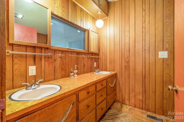 bathroom featuring dual bowl vanity and wooden walls