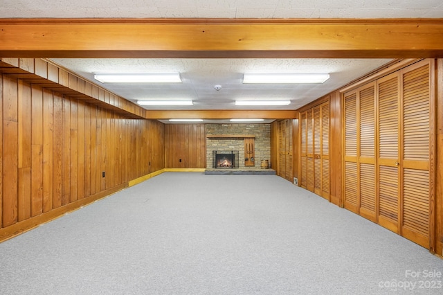 basement with wood walls, a stone fireplace, and carpet